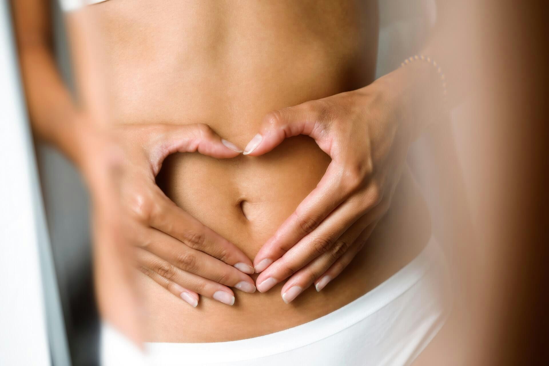 Woman making a heart with her hands on her belly