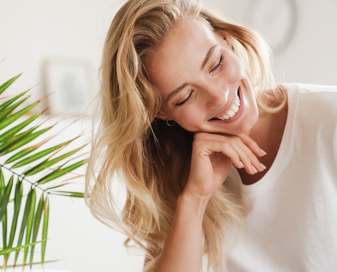 woman head resting on hand while smiling