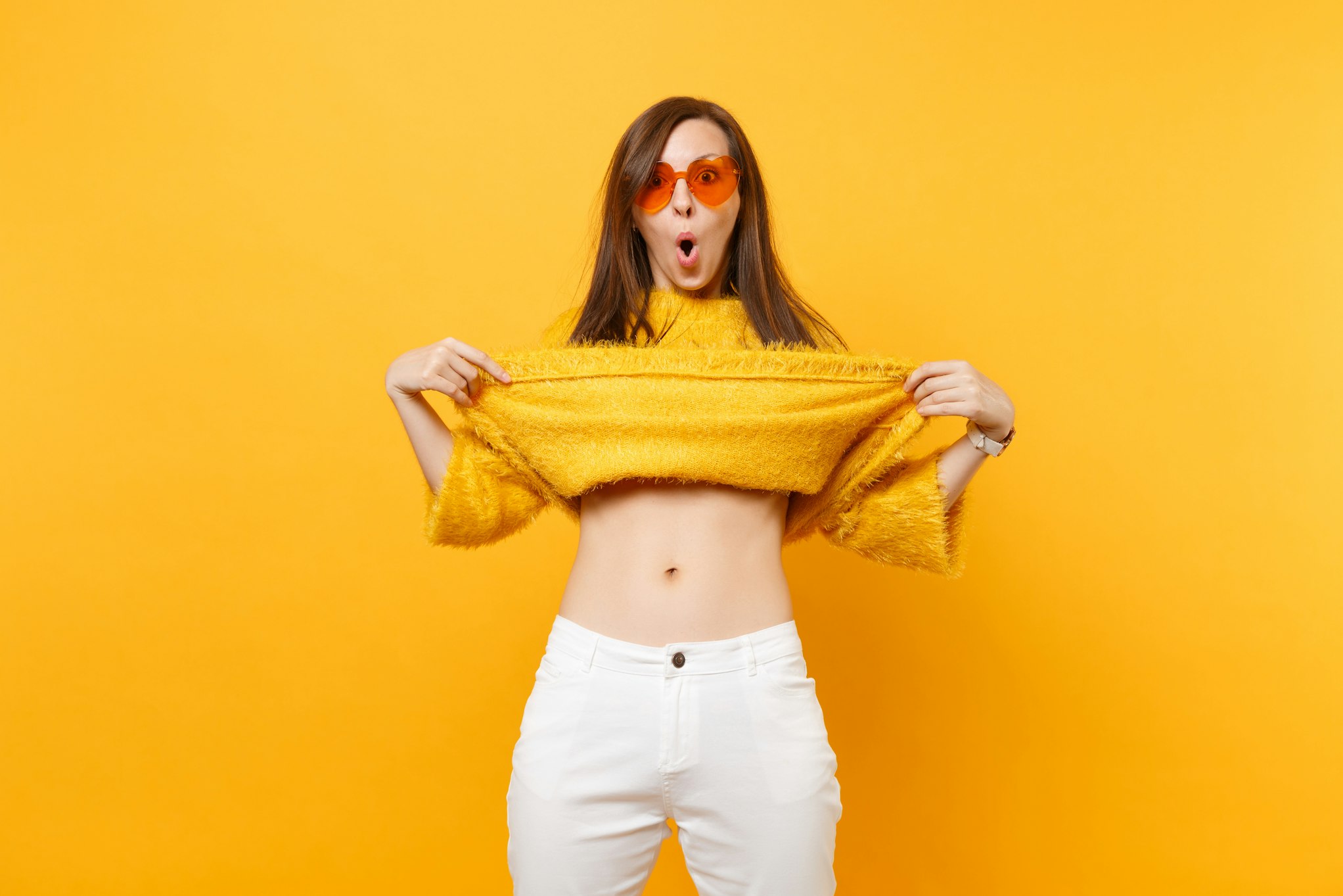 Woman lifting up her yellow sweater to showcase stomach