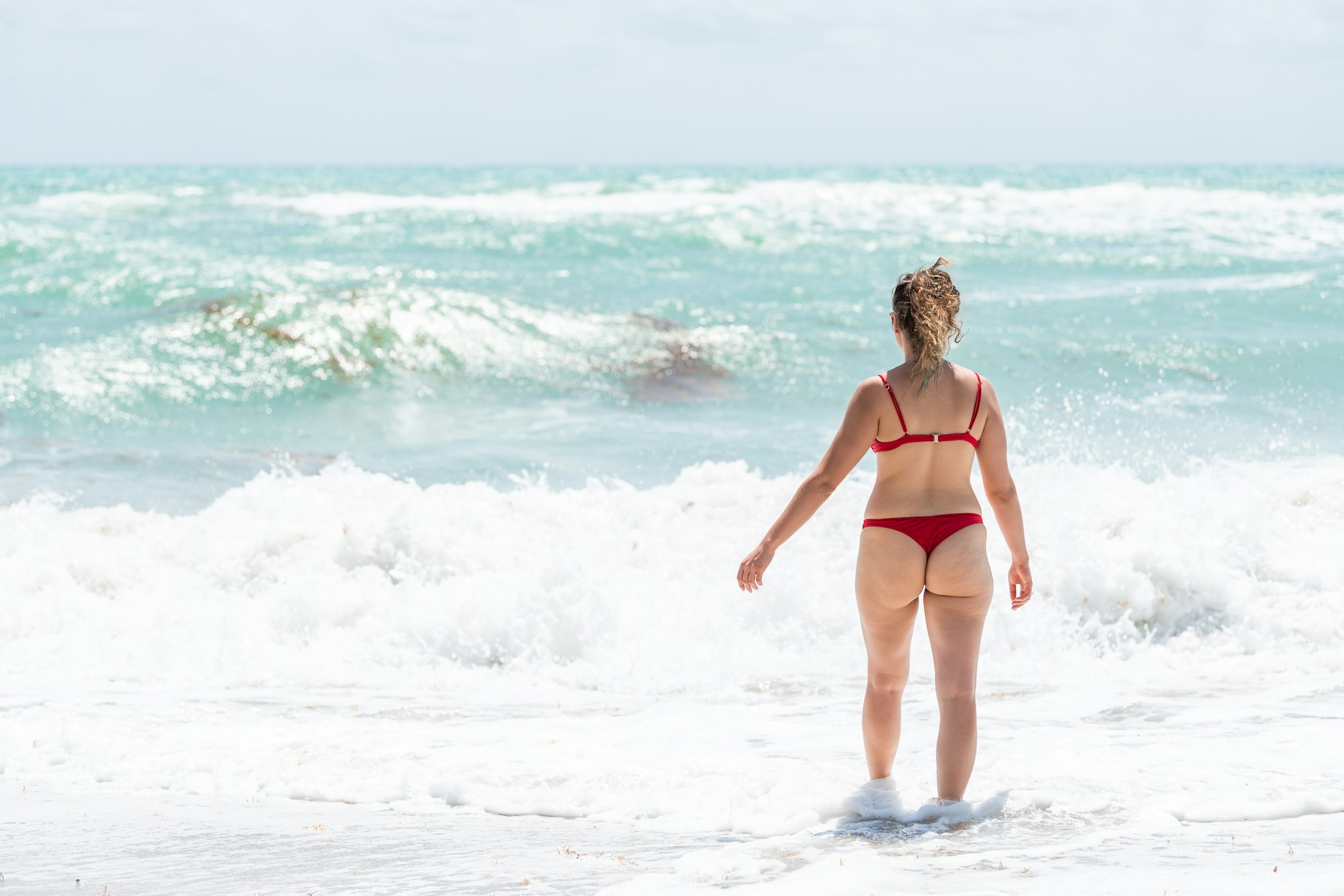 Woman in red bikini walking into the ocean