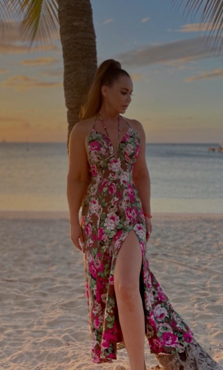 Woman on beach leaning on palm tree