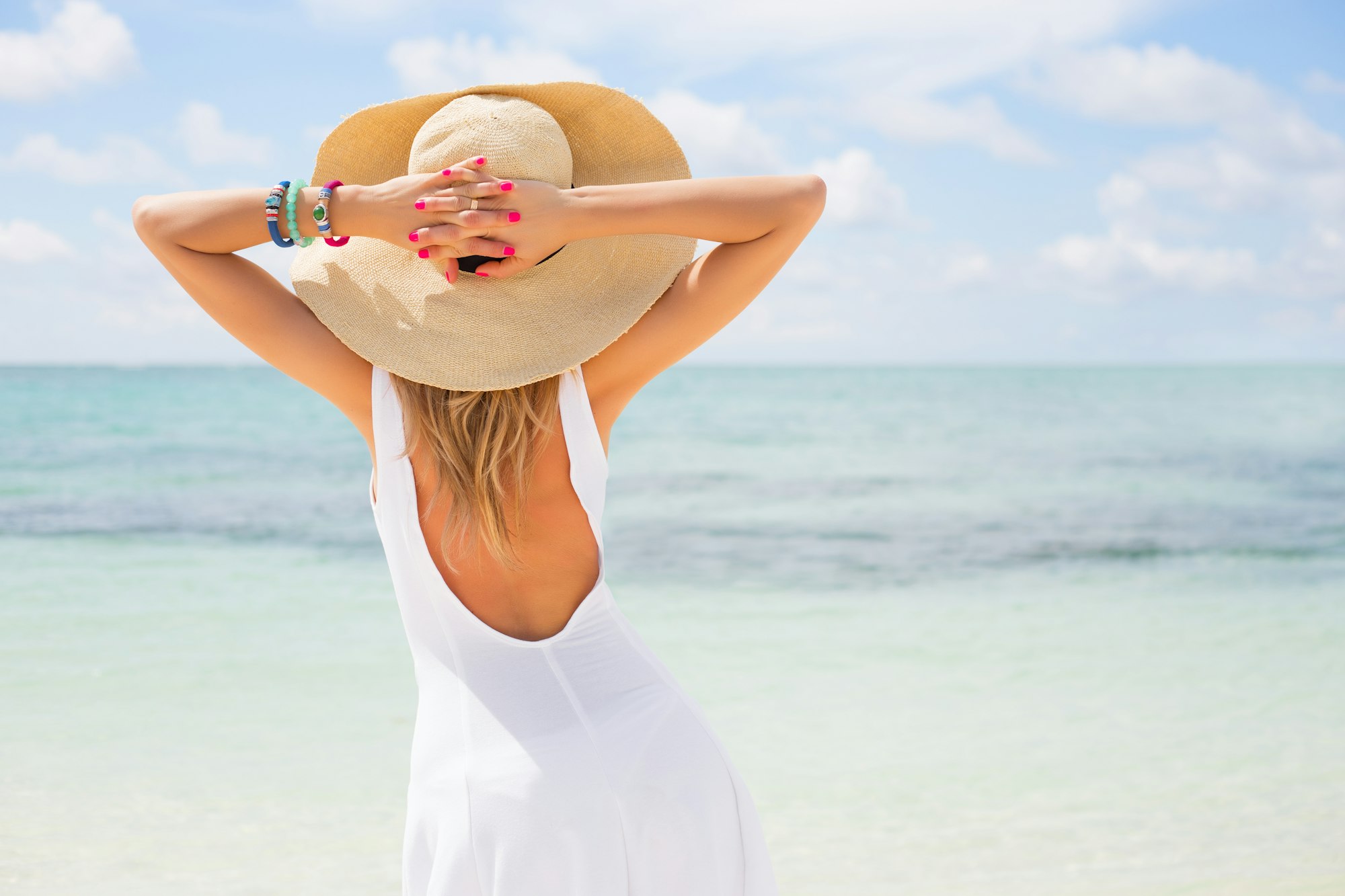 woman in hat facing the beach