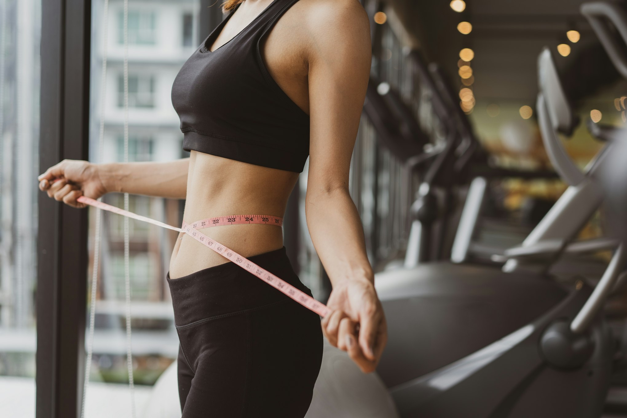 woman measuring waist at gym