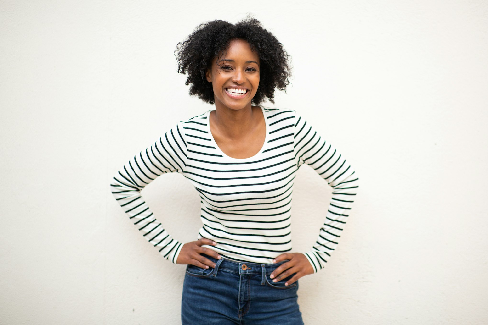 Woman in stripped shirt with hands on hips smiling