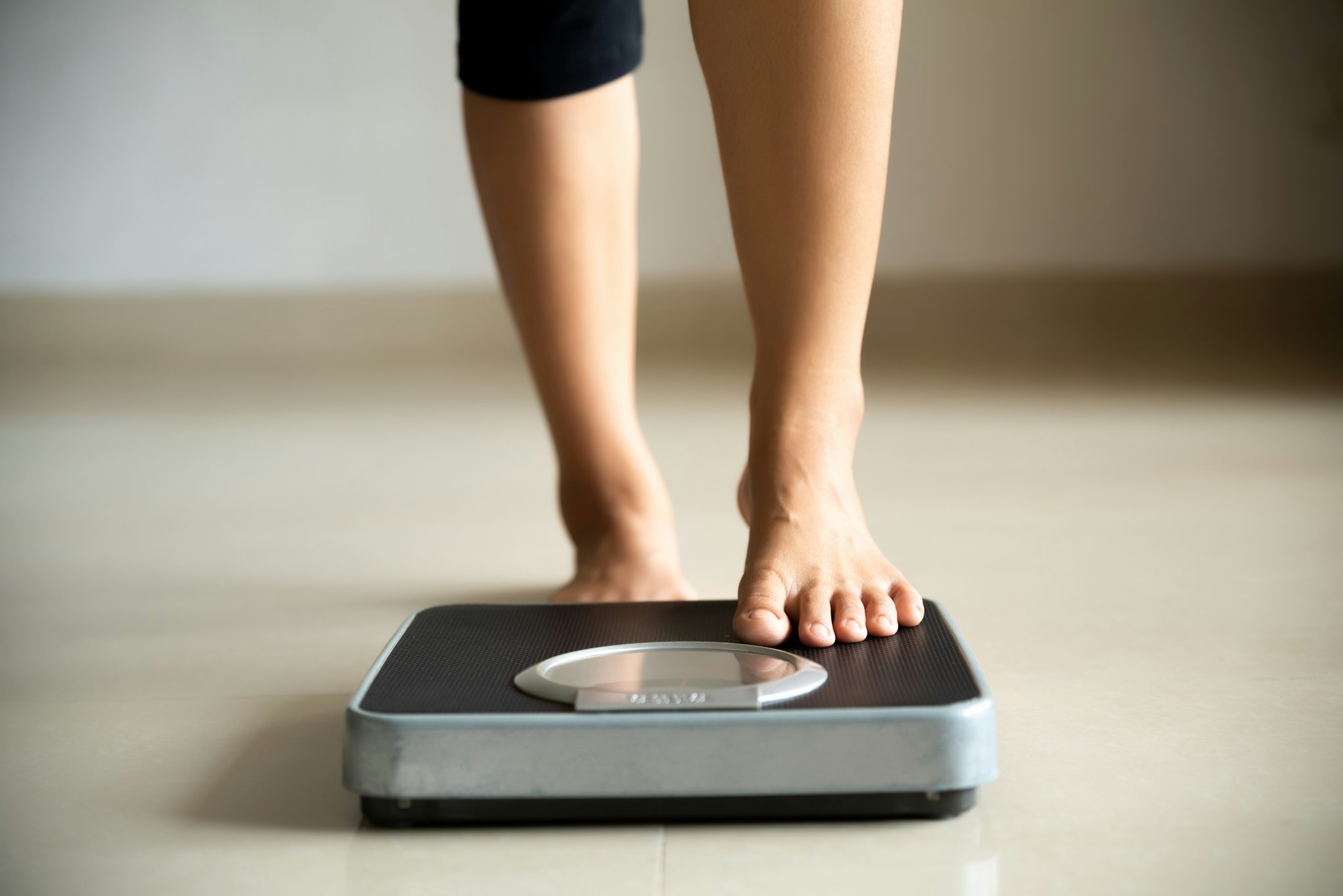 Female leg stepping on weigh scales.