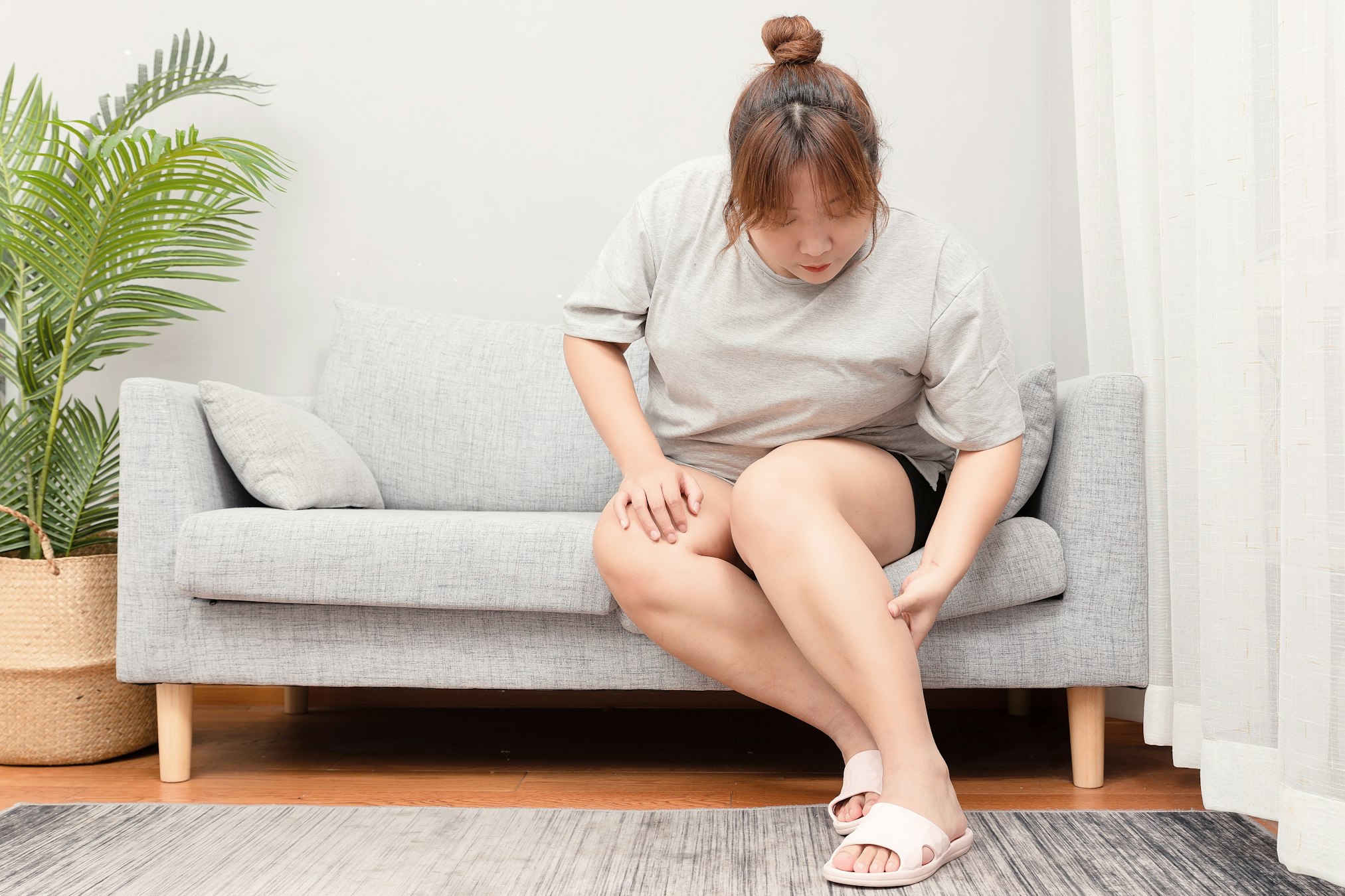 Asian fat girl sitting on the sofa holding calf
