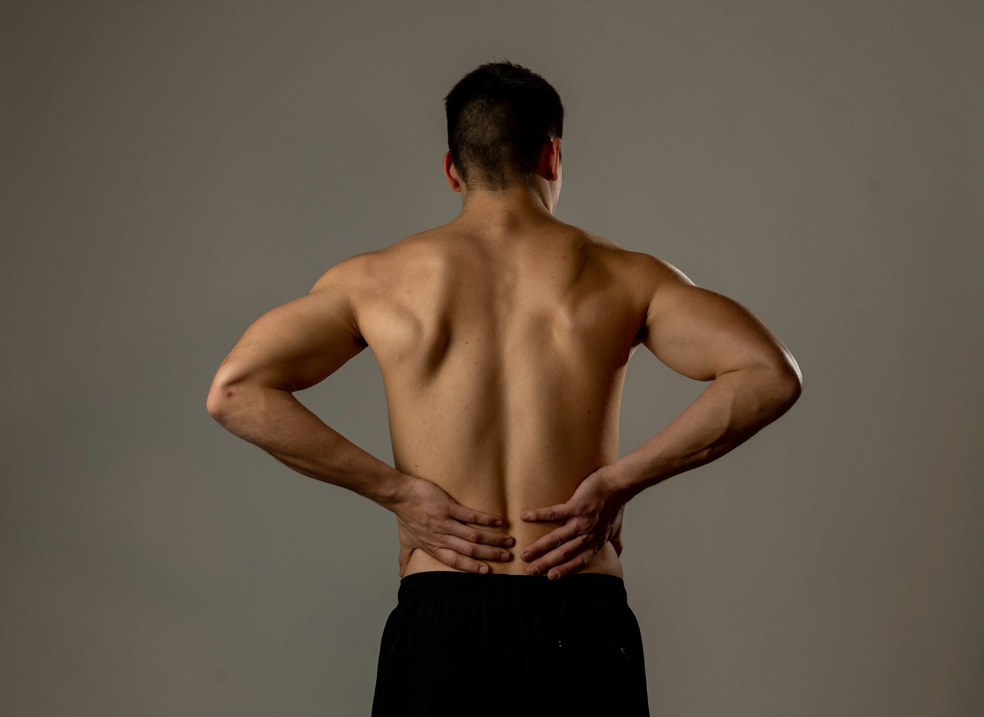 Strong young man suffering lower back pain in stress and bad posture