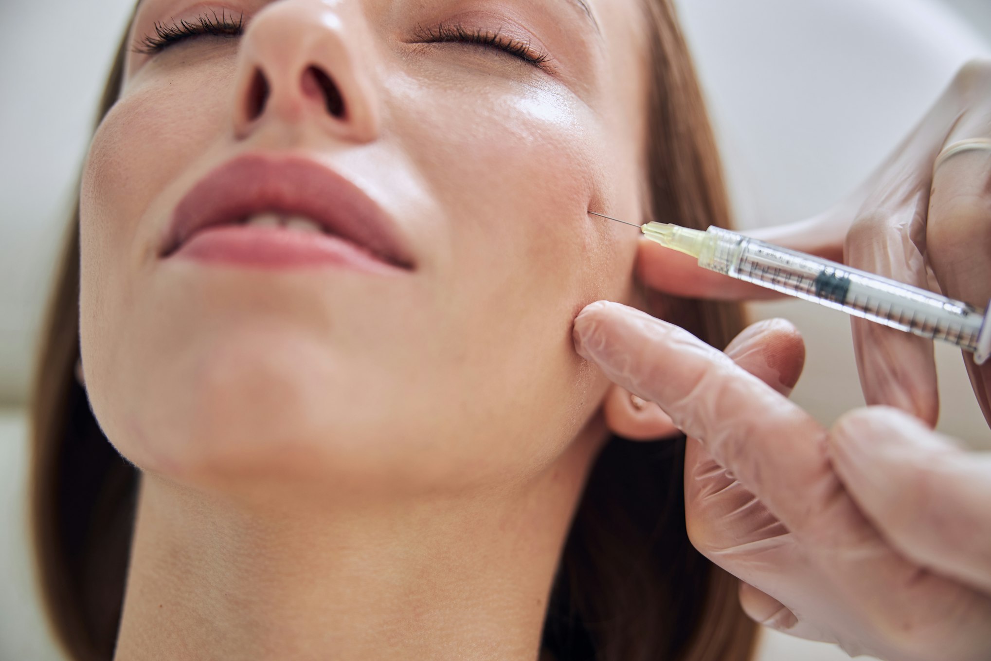 Beautiful young Caucasian female getting hyaluronic aced skincare in cosmetic clinic