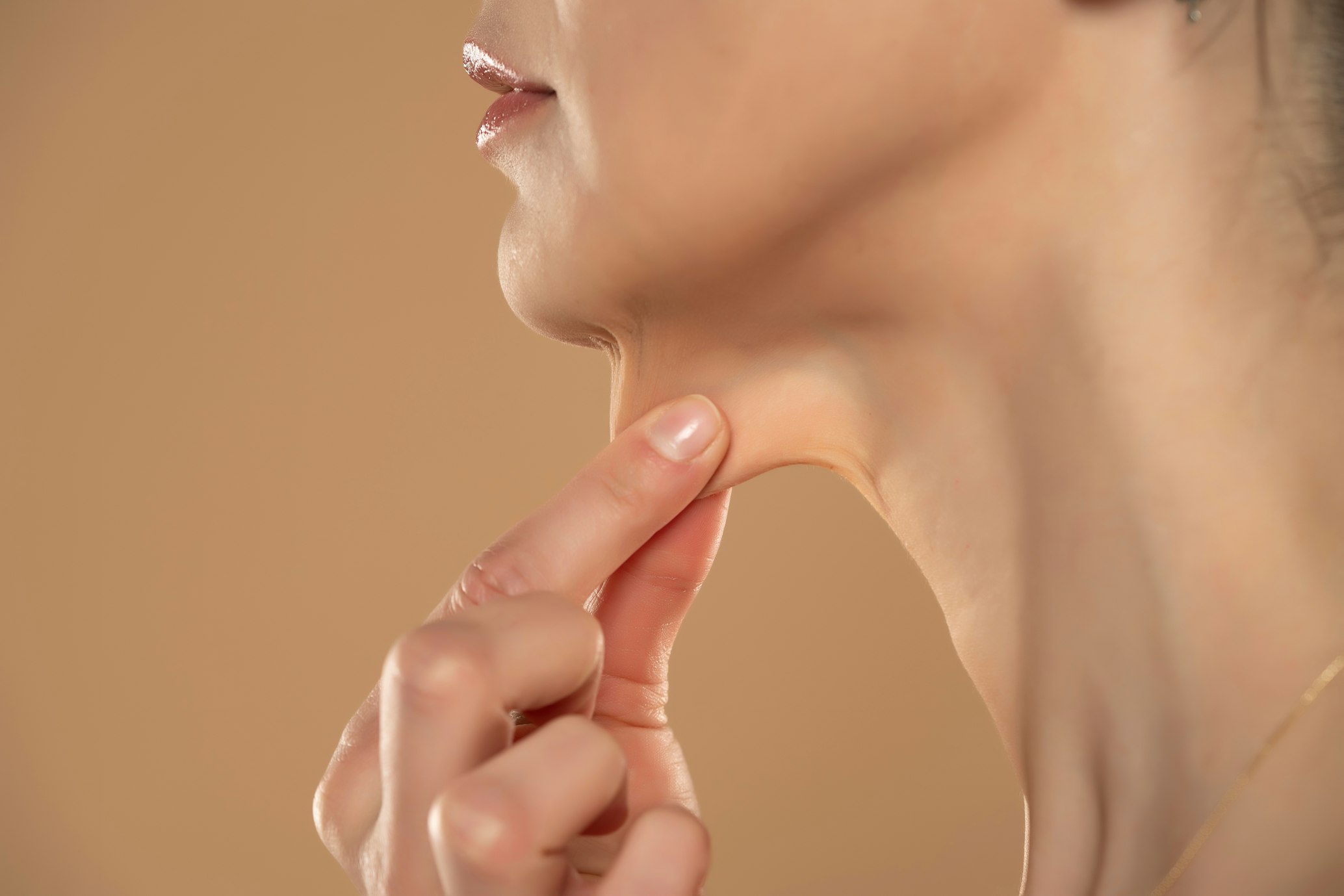 close-up and side profile view of a caucasian lady pinching the loose skin at the front of her throat.