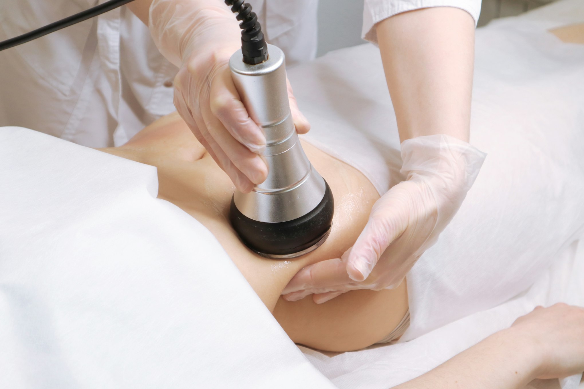 Beautician makes the procedure cavitation of a young beautiful girl