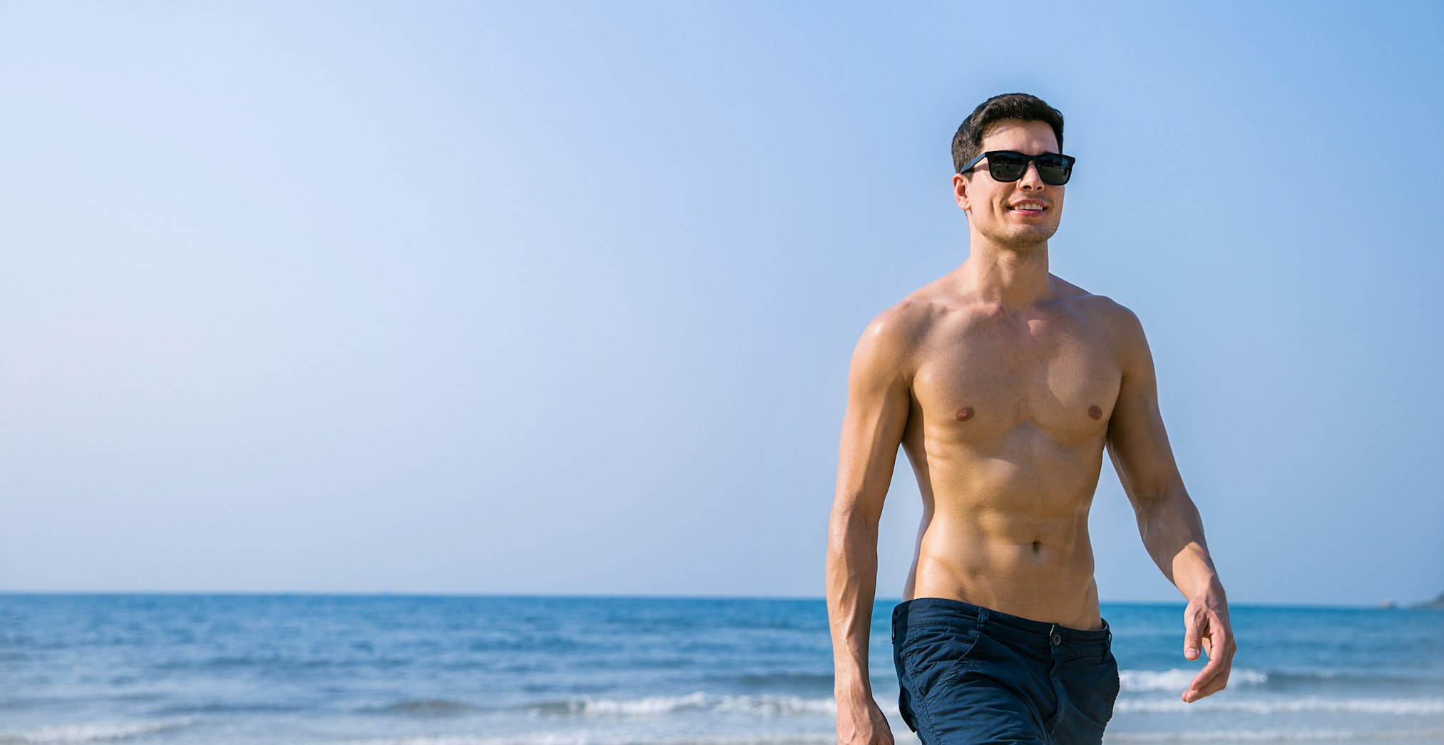 Young healthy skin sun tan male with slim fit body. Beauty happy guy relax enjoy holiday travel vacation. 20s fitness caucasian man at the beach