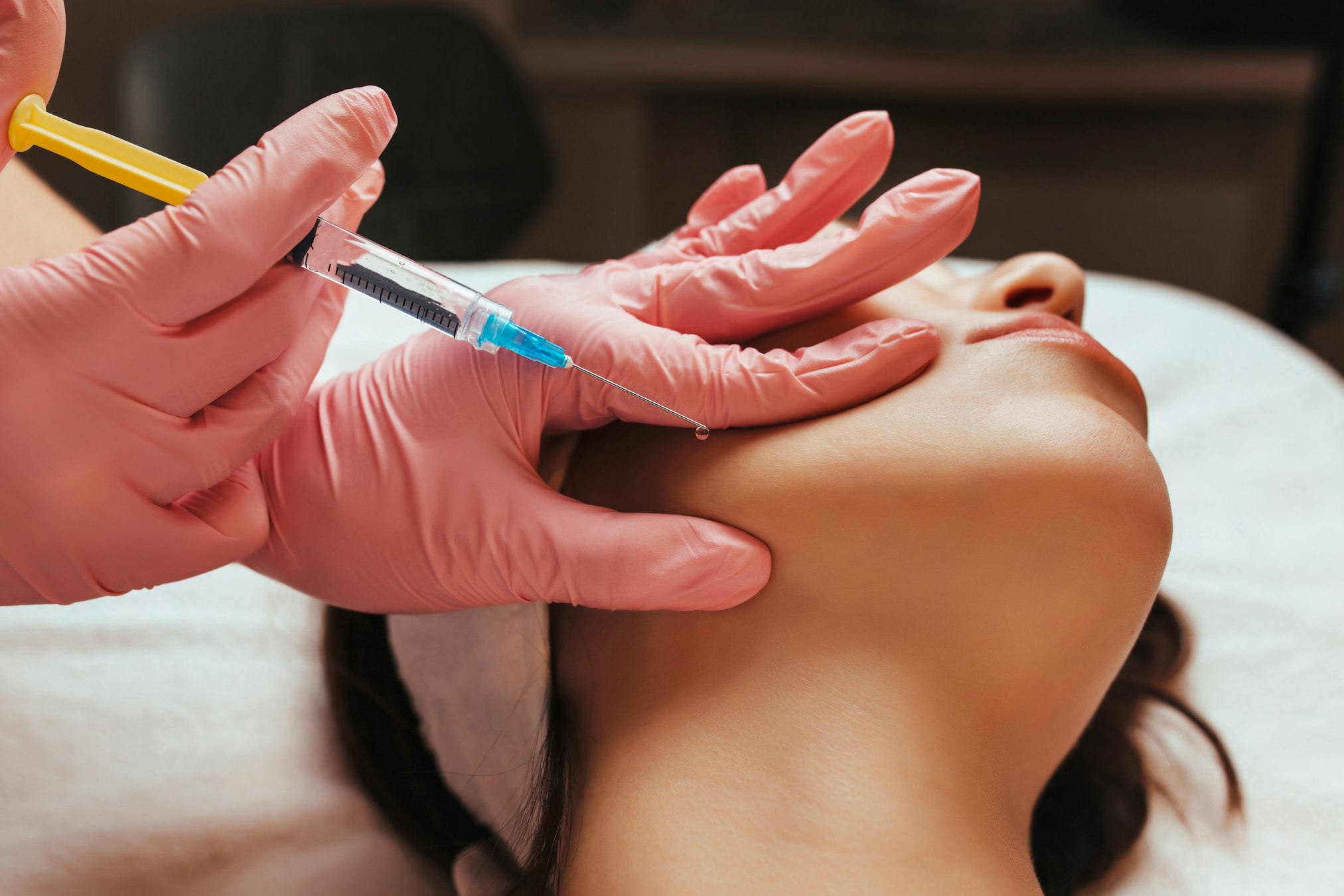 doctor gives an injection into the woman's cheekbone