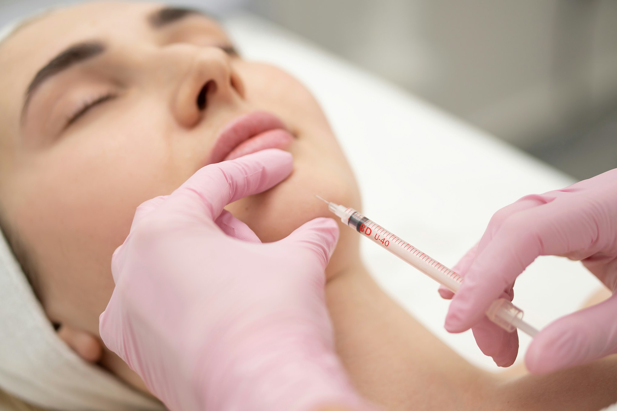 Close-up of the hands of an expert cosmetologist injecting botox into a woman's chin Correction filler . beauty injection concept.