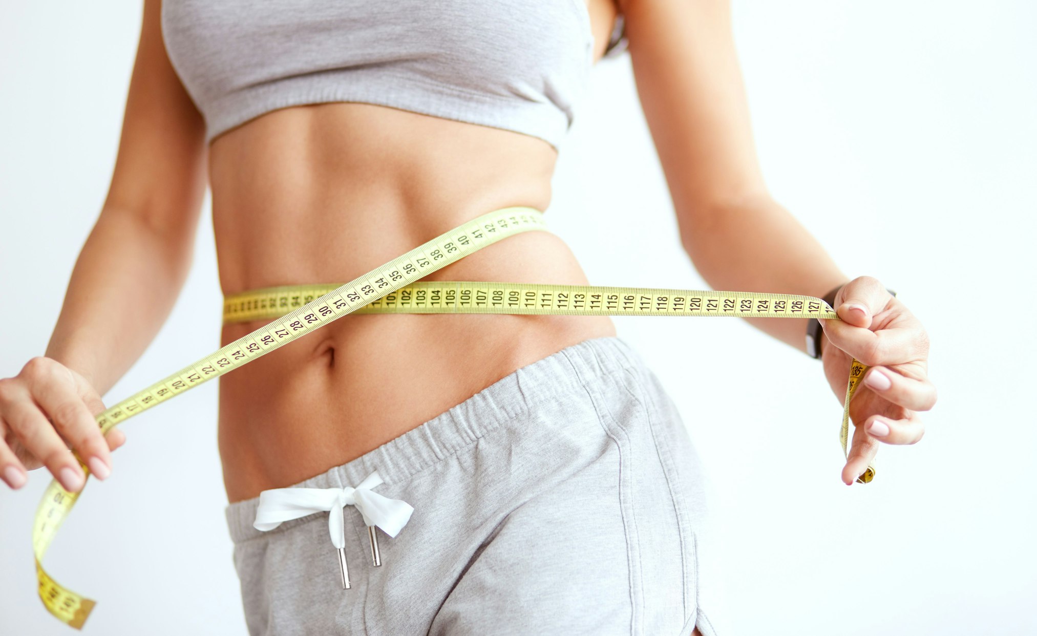 toned woman measuring waist