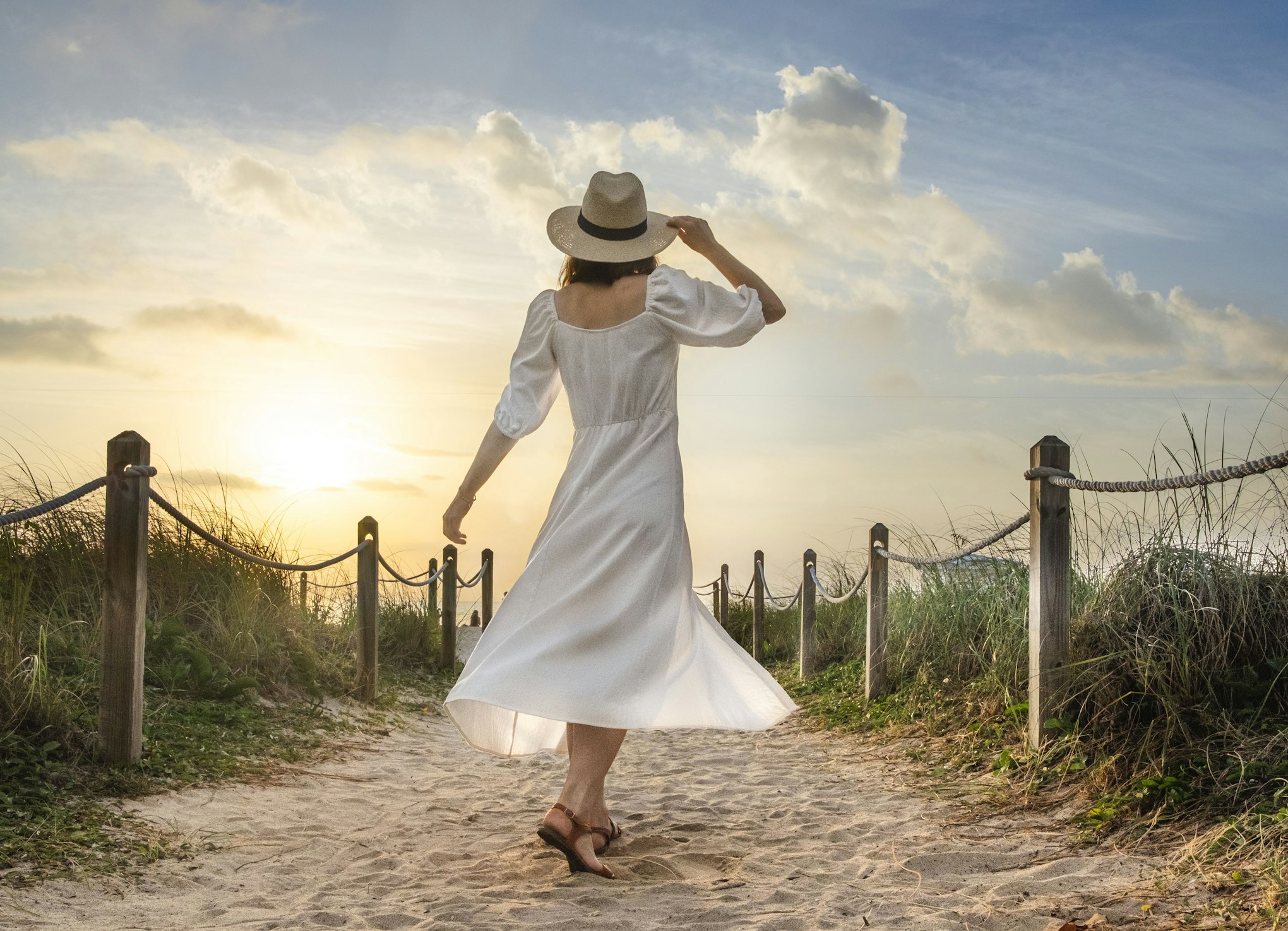 women standing on beach looking at sun