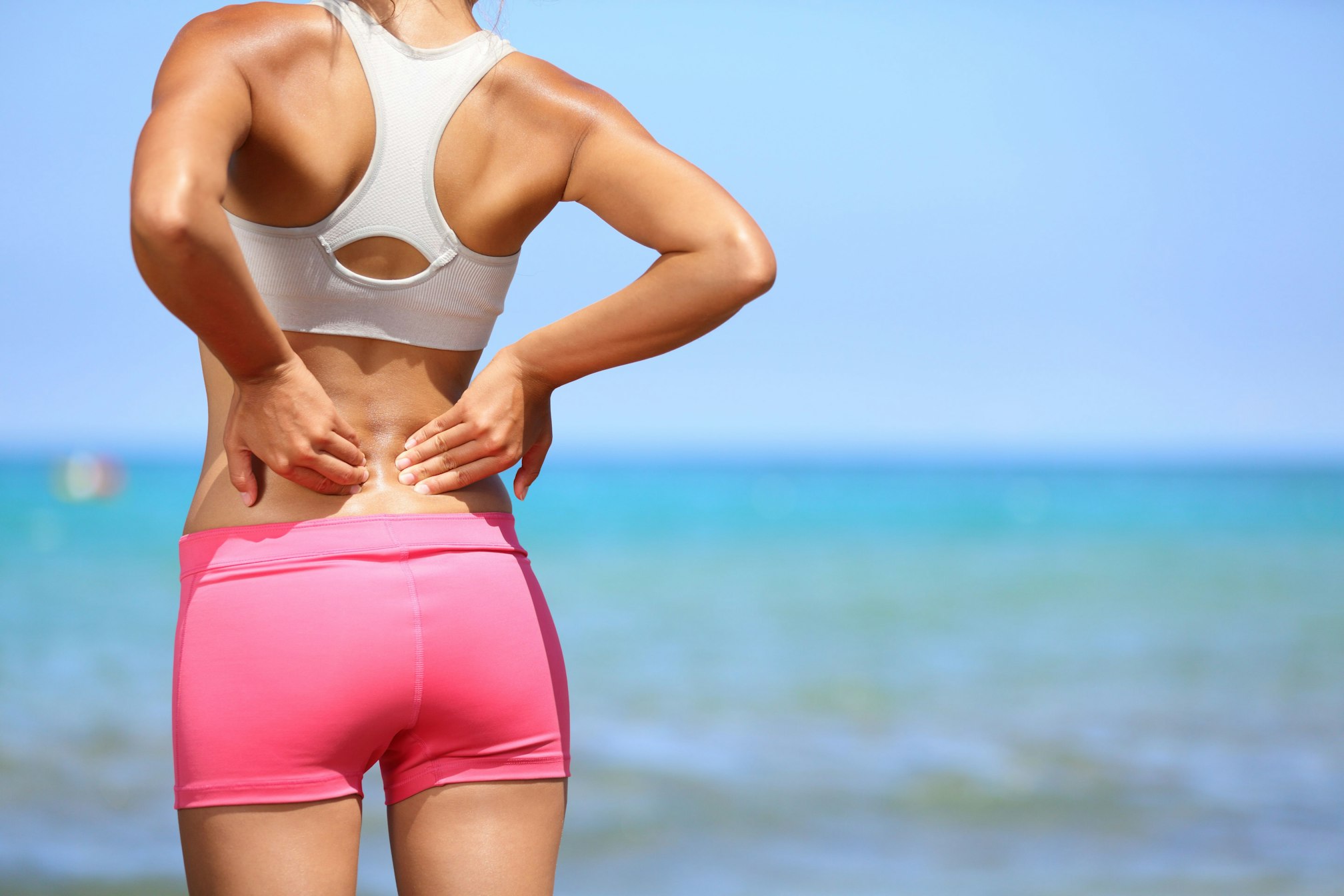 woman stretching back facing the beach