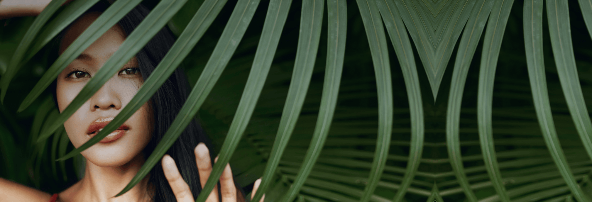 woman peeking behind palm fran