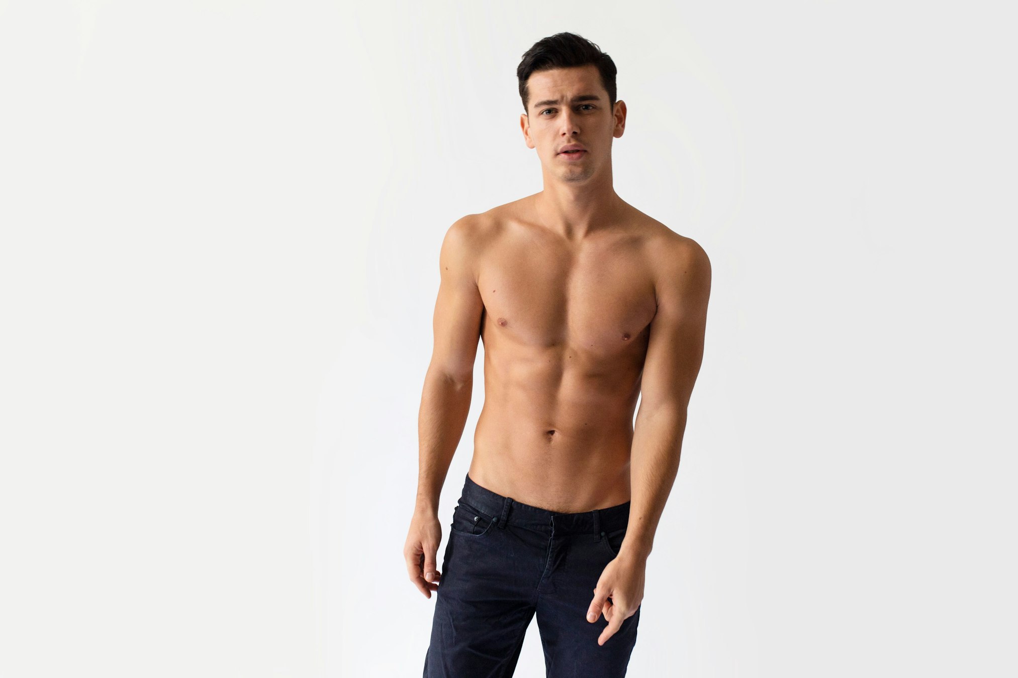 young man with black jeans, posing in studio, looking at camera, isolated on a white background.
