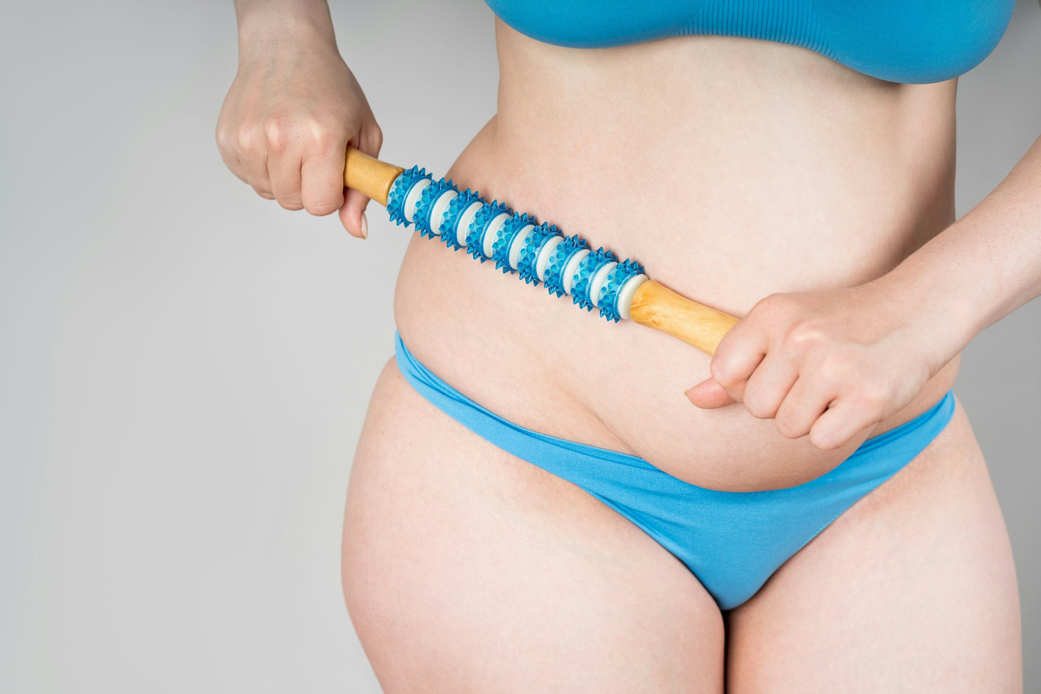 Woman with roller massager on gray background