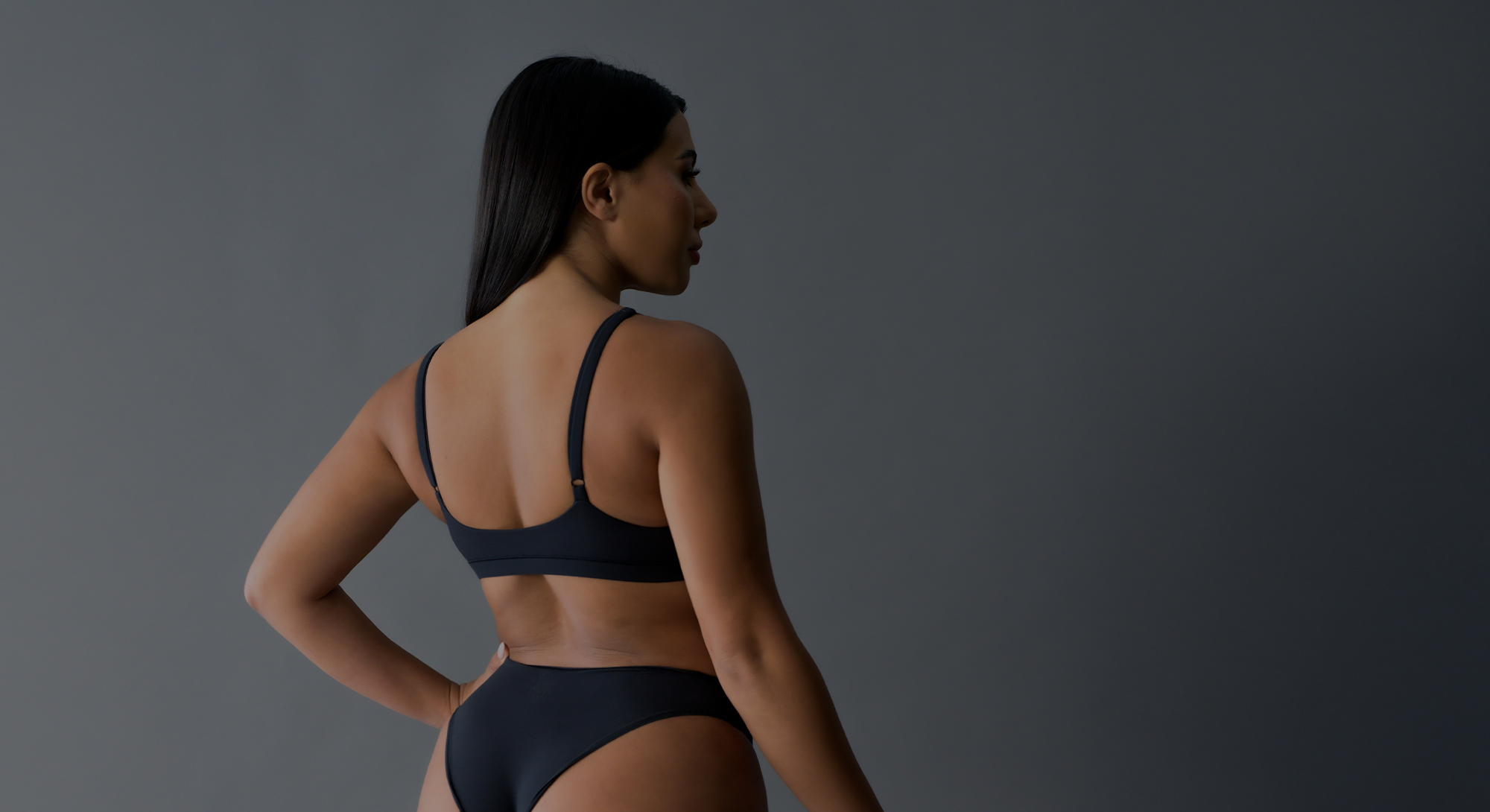 dark, shadowy image of woman in bikini viewed from behind