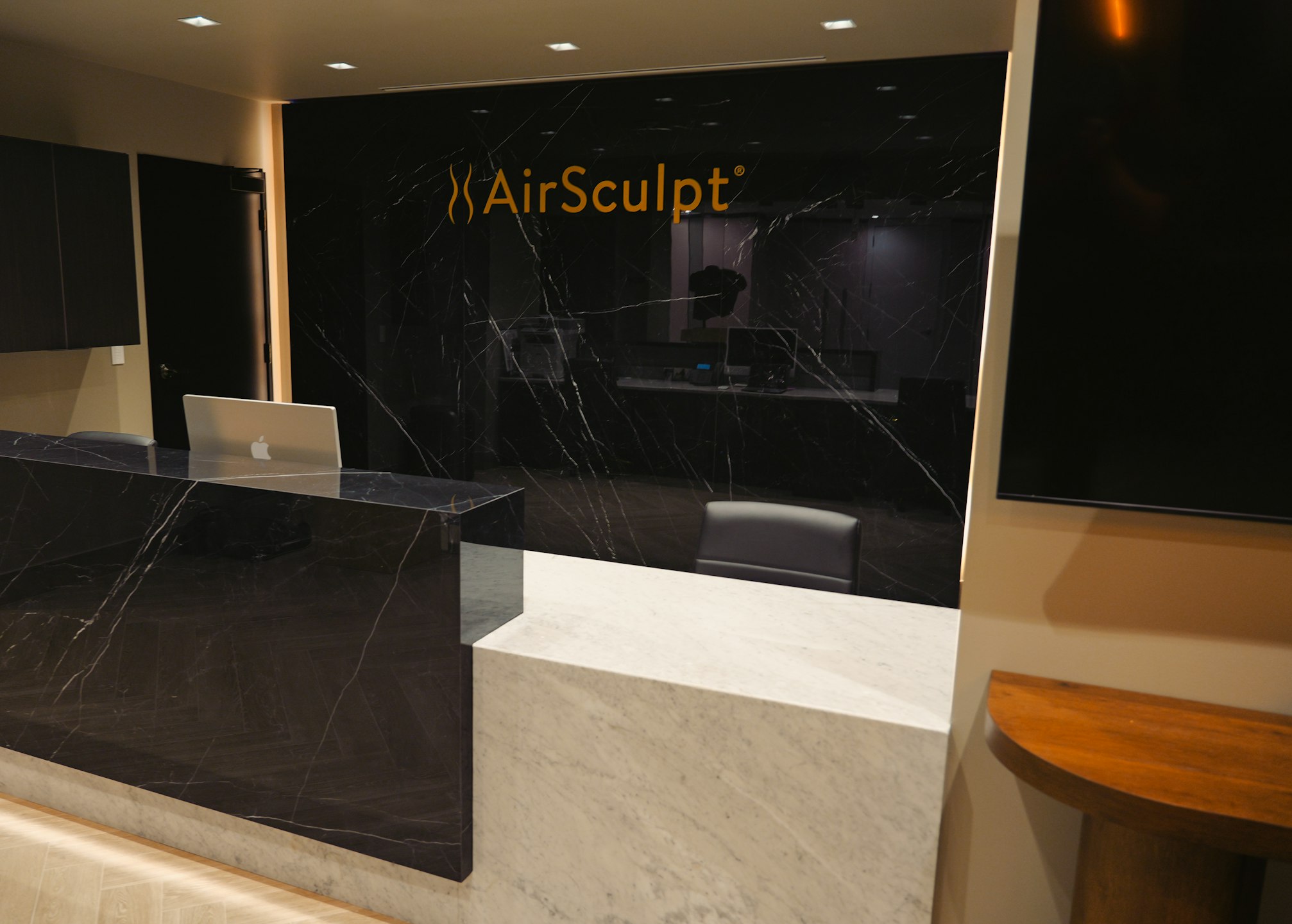 Front desk and backdrop featuring AirSculpt logo in AirSculpt Body Contouring Birmingham clinic lobby
