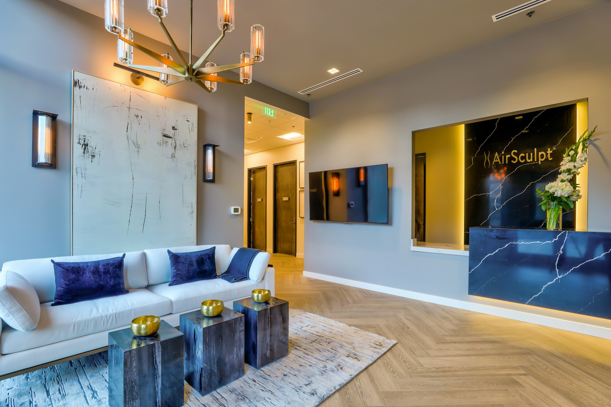 Couch, marble accent wall, and chandelier in AirSculpt Body Contouring Denver clinic lobby
