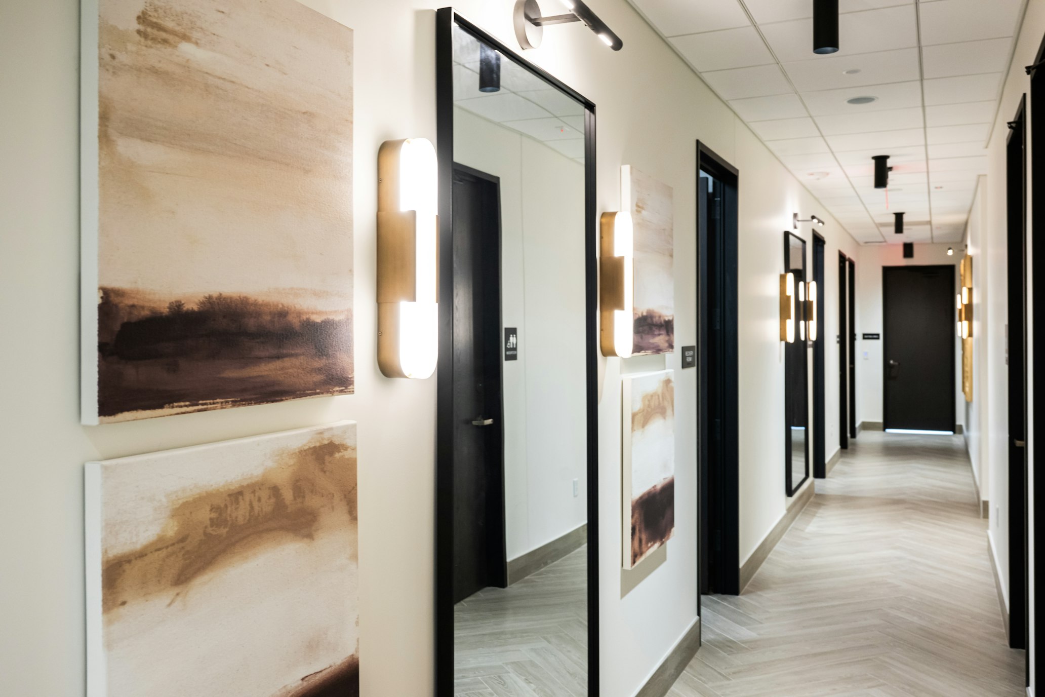 Hallway with framed artwork and wall sconces in AirSculpt Body Contouring Kansas City clinic