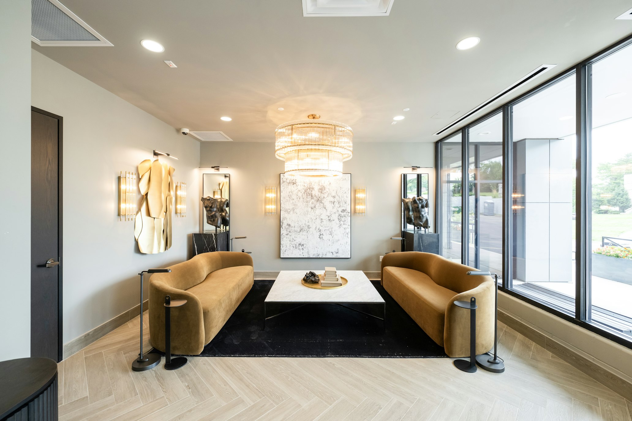 Two velvet couches facing a low table beneath a chandelier in AirSculpt Body Contouring Kansas City clinic lobby