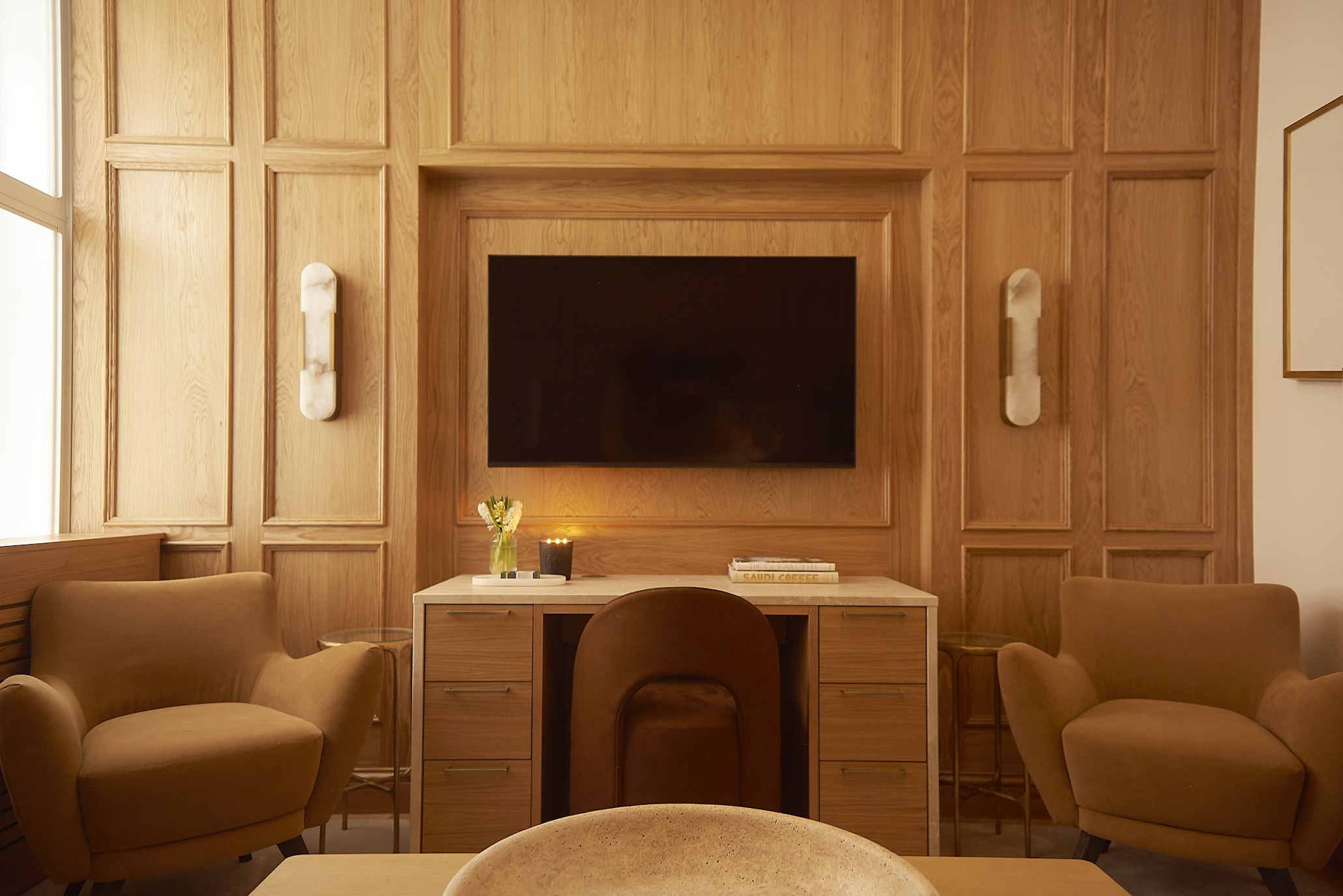 Wood‑paneled consultation room with desk and wall‑mounted television in Elite Body Sculpture London clinic consultation room
