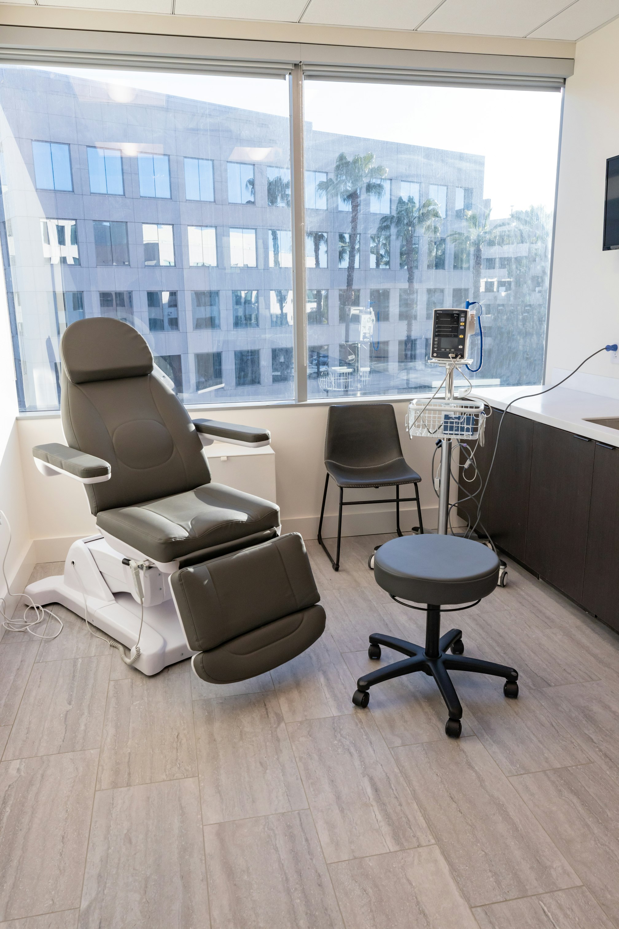 Recovery room with medical chair and floor‑to‑ceiling window in AirSculpt Body Contouring Orange County clinic