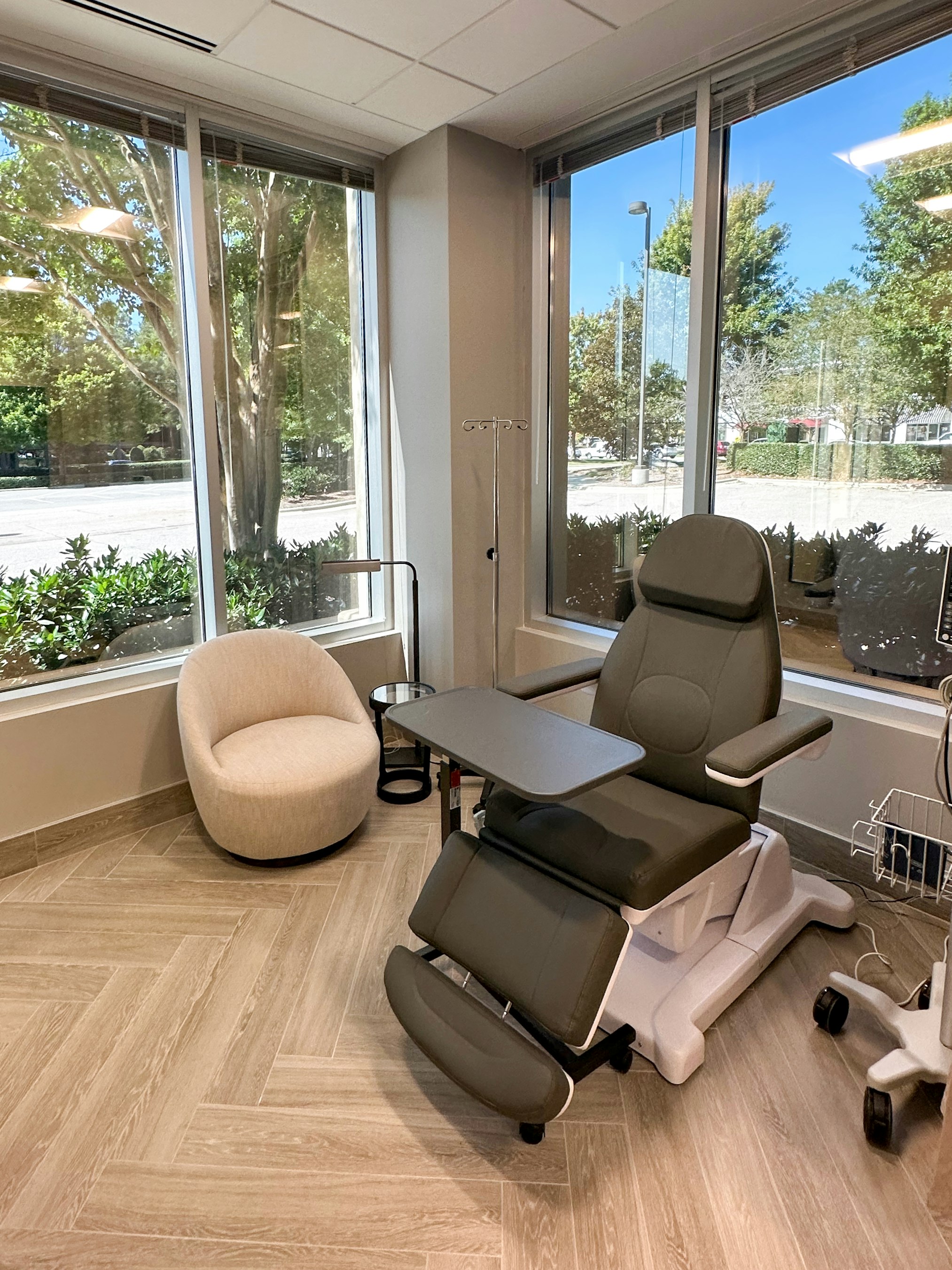 Recovery room with exam chair and floor‑to‑ceiling windows in AirSculpt Body Contouring Raleigh clinic