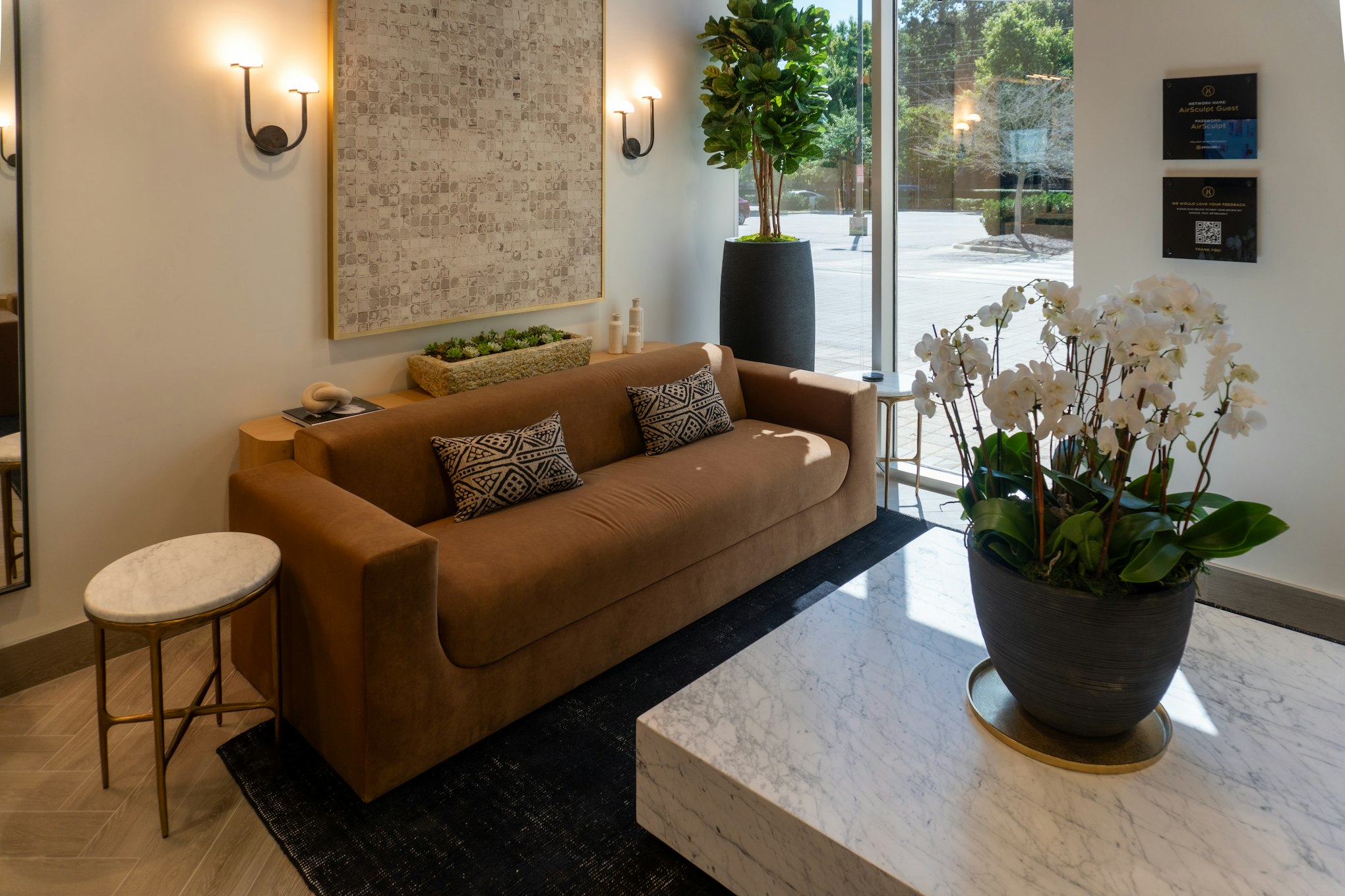 Couch, artwork, and potted plant in AirSculpt Body Contouring Raleigh clinic waiting area