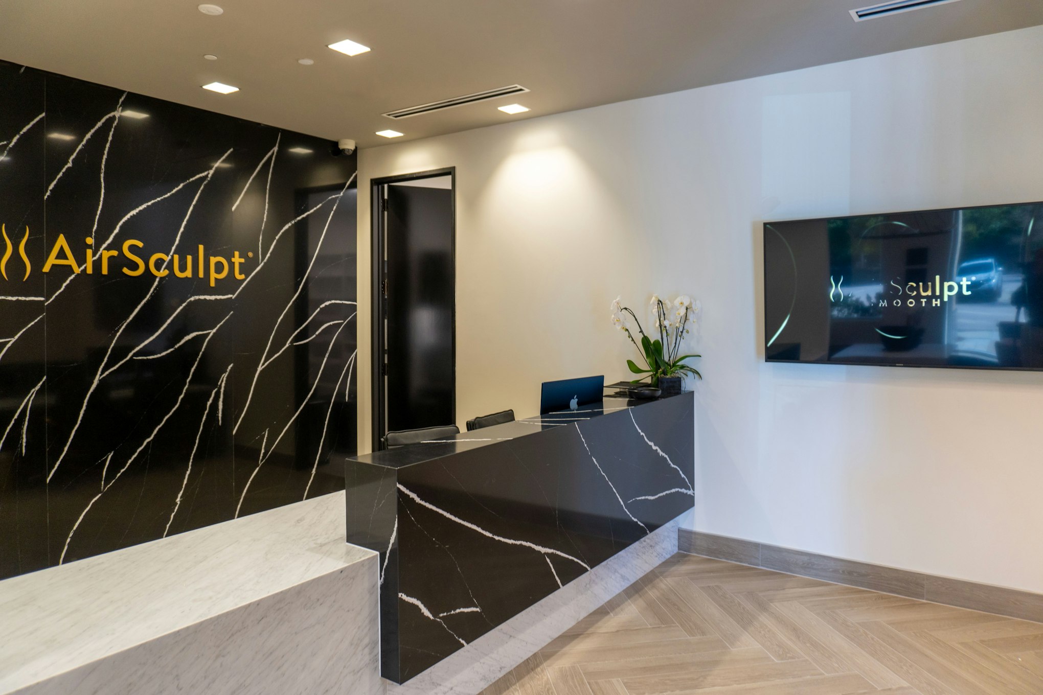 Front desk and backdrop featuring AirSculpt logo in AirSculpt Body Contouring Raleigh clinic lobby