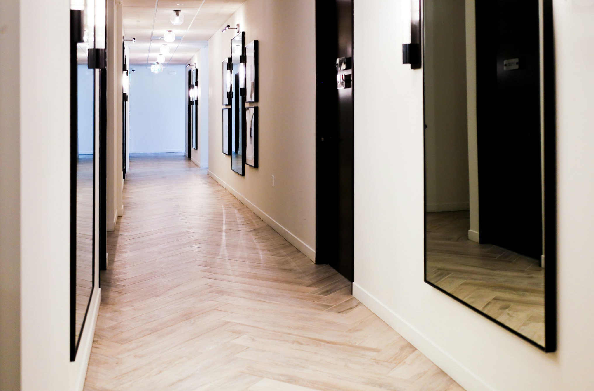 Hallway with framed artwork and herringbone wood floor in AirSculpt Body Contouring Sacramento clinic