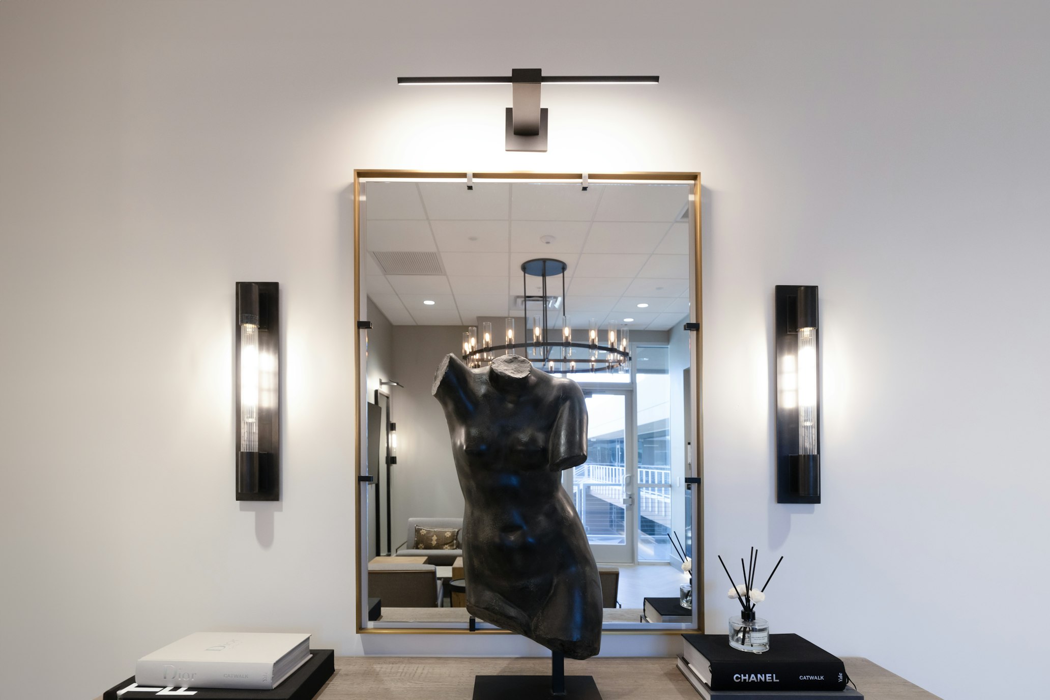 Decorative mannequin bust and mirror with wall sconces in AirSculpt Body Contouring Scottsdale clinic lobby