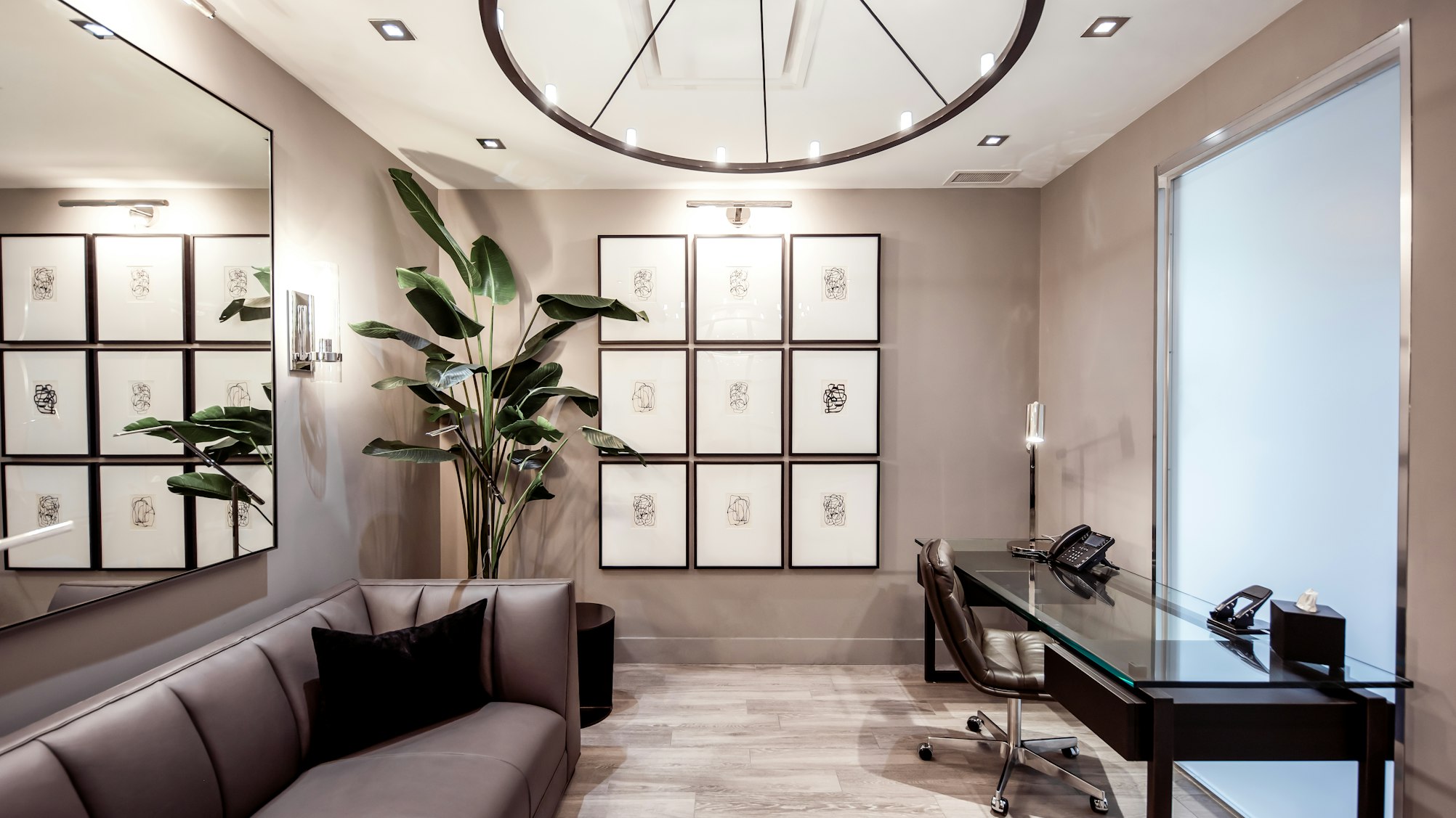Couch and framed artwork with potted plant in Elite Body Sculpture Toronto clinic waiting area