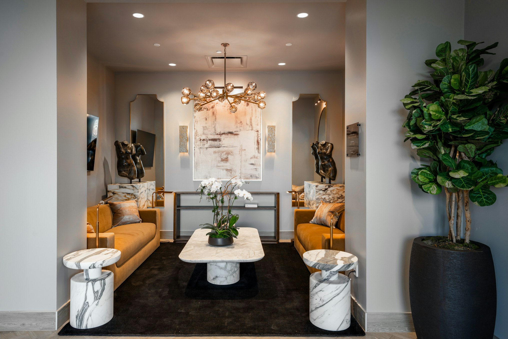 Couches, an elegant chandelier, marbled tables, and two sculptures of a torso within AirSculpt Body Contouring Deerfield clinic lobby
