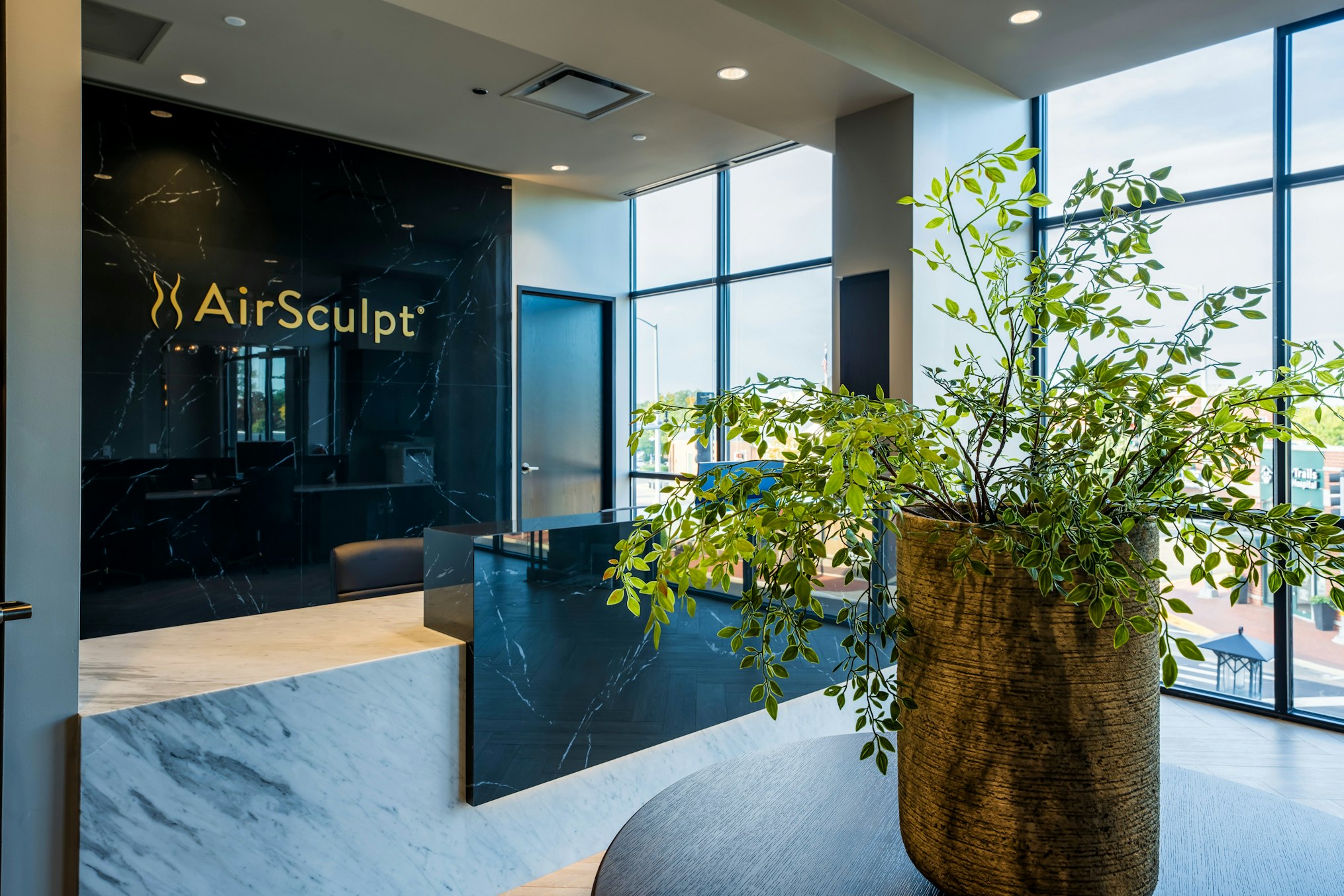 Front desk and backdrop featuring AirSculpt logo in AirSculpt Body Contouring Deerfield clinic lobby