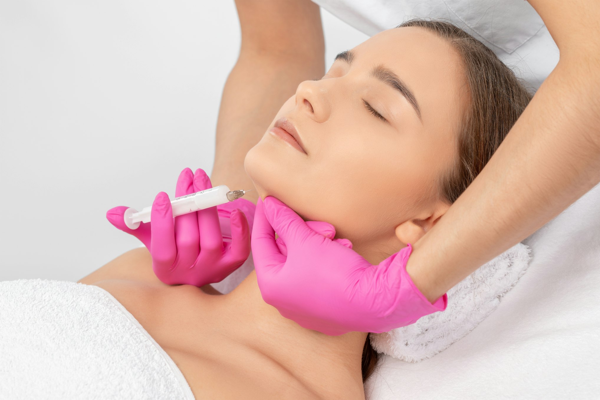 Cosmetologist makes lipolytic injections to burn fat on the chin, cheeks and neck of a woman against double chin.
