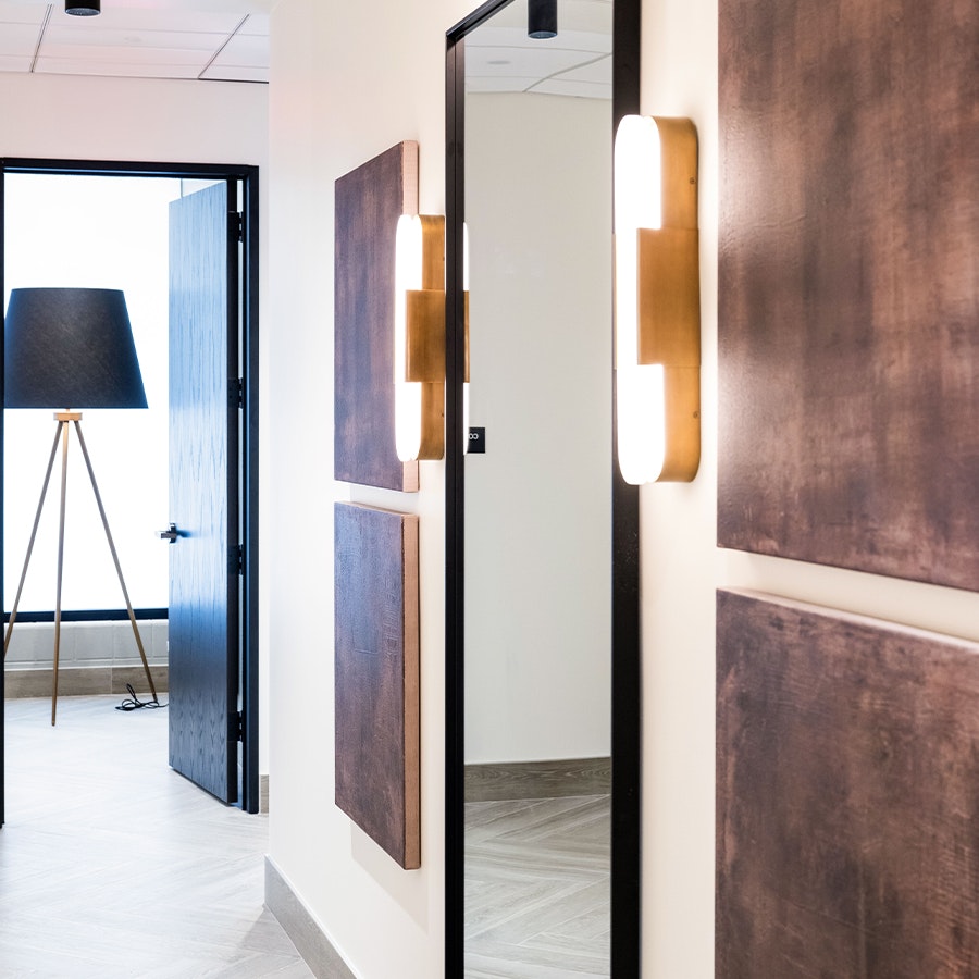 Hallway with mirrored panels and wall sconces in AirSculpt Body Body Contouring Clinic corridor