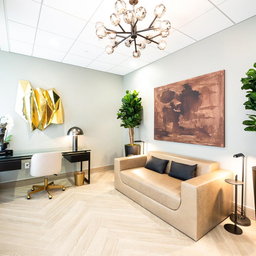 Couch, coffee table, chandelier, and framed artwork in AirSculpt Body Body Contouring Clinic consultation room