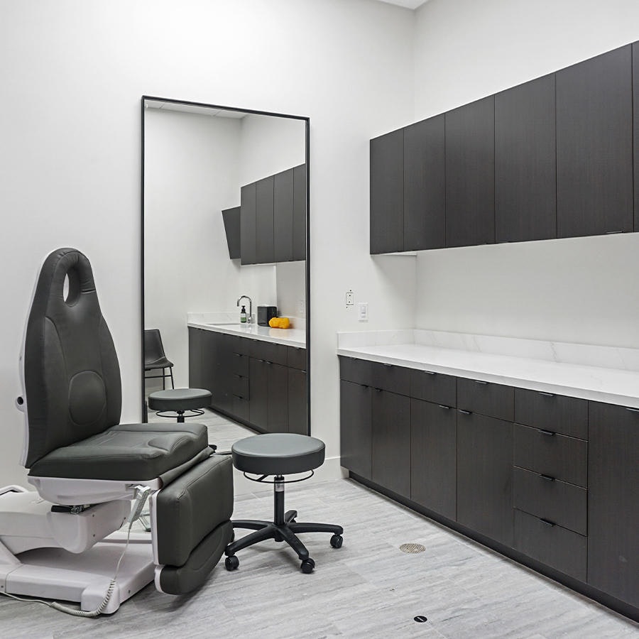 Operating room with medical chair, countertop, and cabinetry in AirSculpt Body Body Contouring Clinic