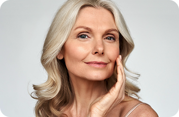 Older woman touching her cheek after facial rejuvenation treatment.