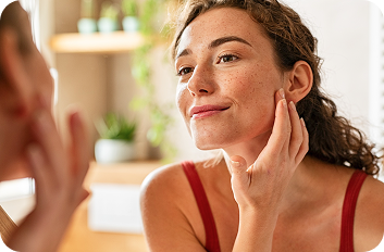 Woman examining her chin and jawline in a mirror.