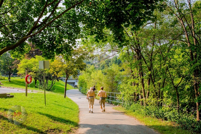 Two shirtless men jogging on a trail in a park