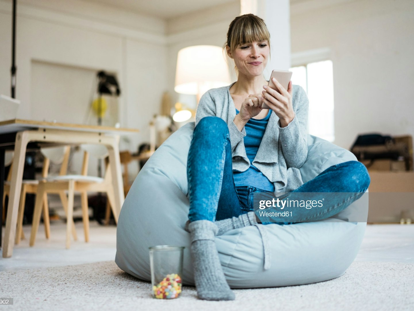 Smiling woman sitting in beanbag using cell phone