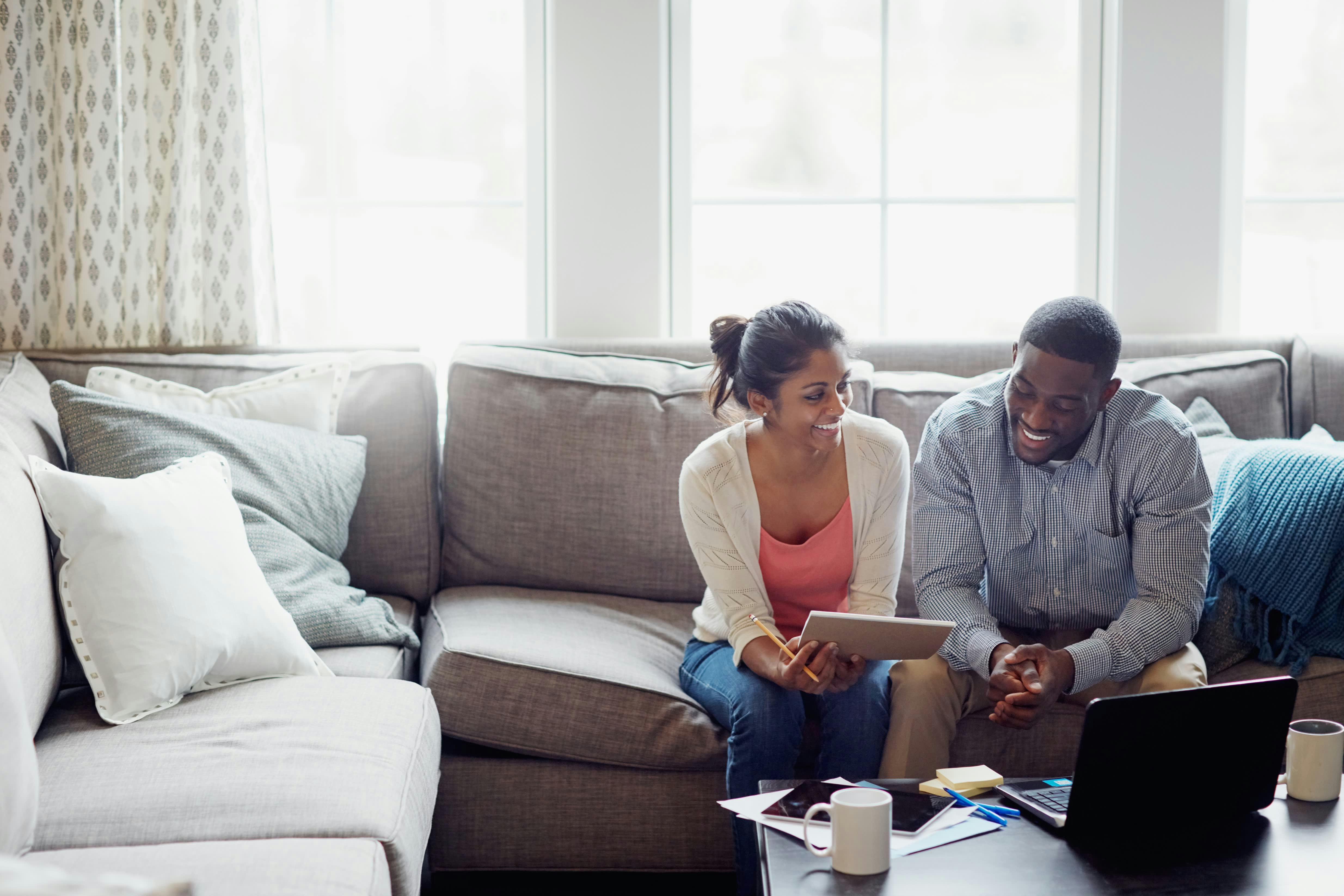 A young couple going through paperwork together on the sofa at home