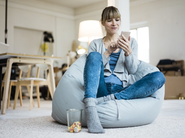 Smiling woman sitting in beanbag using cell phone