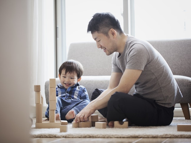 An Asian father and son playing with blocks sitting on floor