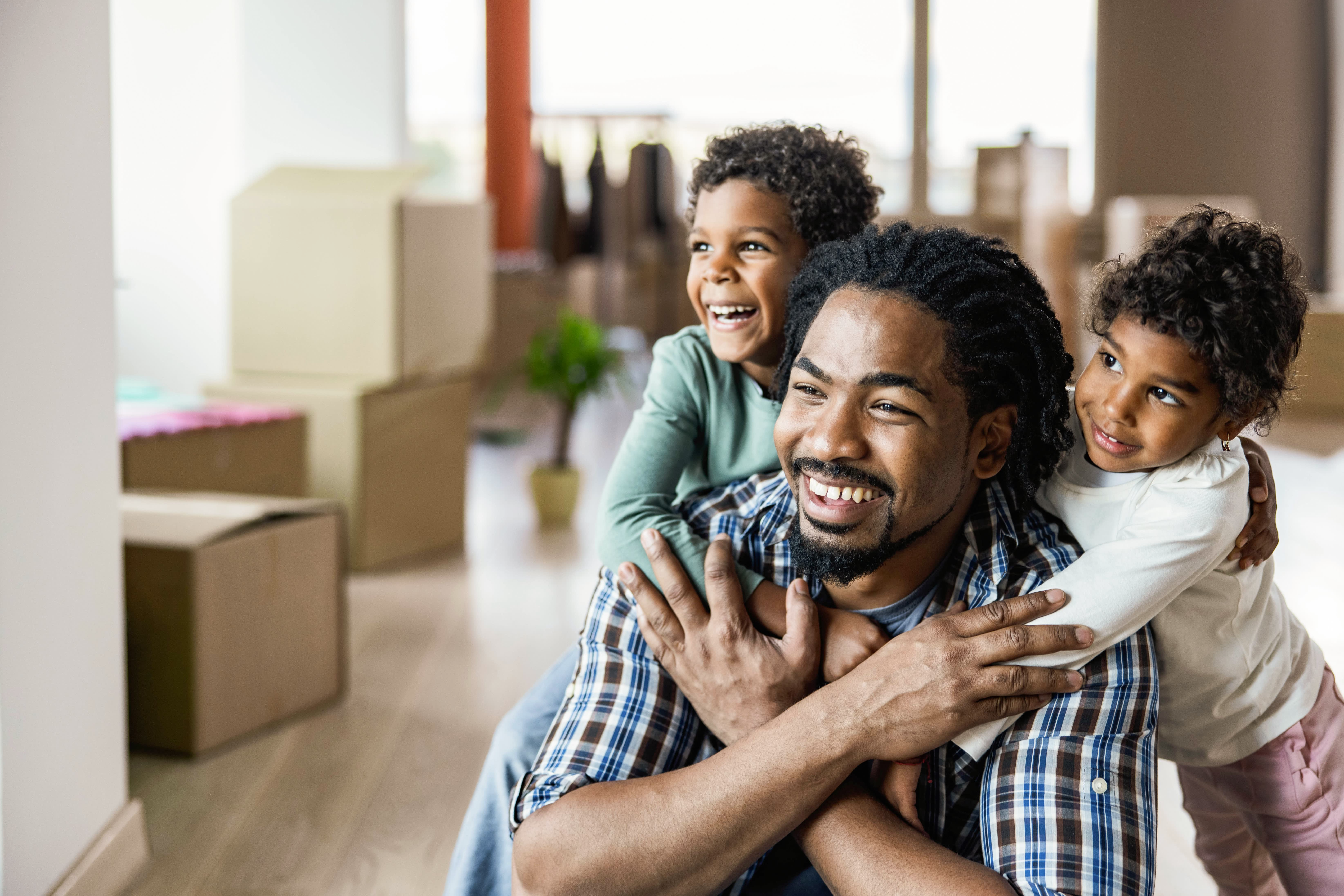 Happy African American kids embracing their single father at new apartment